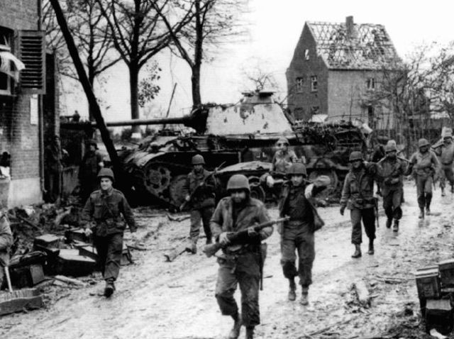 Patrulla de infantería blindada de la 2ª División Blindada pasa junto a un Panther de la 9ª Panzer-Division puesto fuera de combate en Immendorff. 16 noviembre 1944