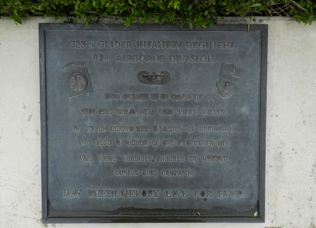 Conjunto memorial compuesto por varias placas conmemorativas, paneles descriptivos y una estatua de un Iron Mike en el puente sobre el río Merderet