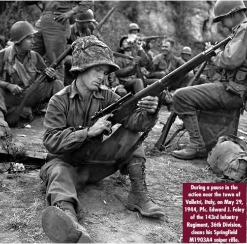 Soldado de la 36ª División de Infantería limpiando su fusil Springfield M1903A4 de francotirador
