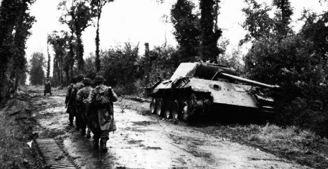 Infantería británica pasando junto a un Panther Ausf. A puesto fuera de combate en la carretera de Tilly-sur-Seulles. Normandía, junio de 1944
