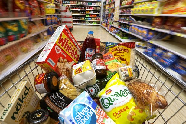 Groceries-in-a-shopping-trolley-move-through-a-food-aisle